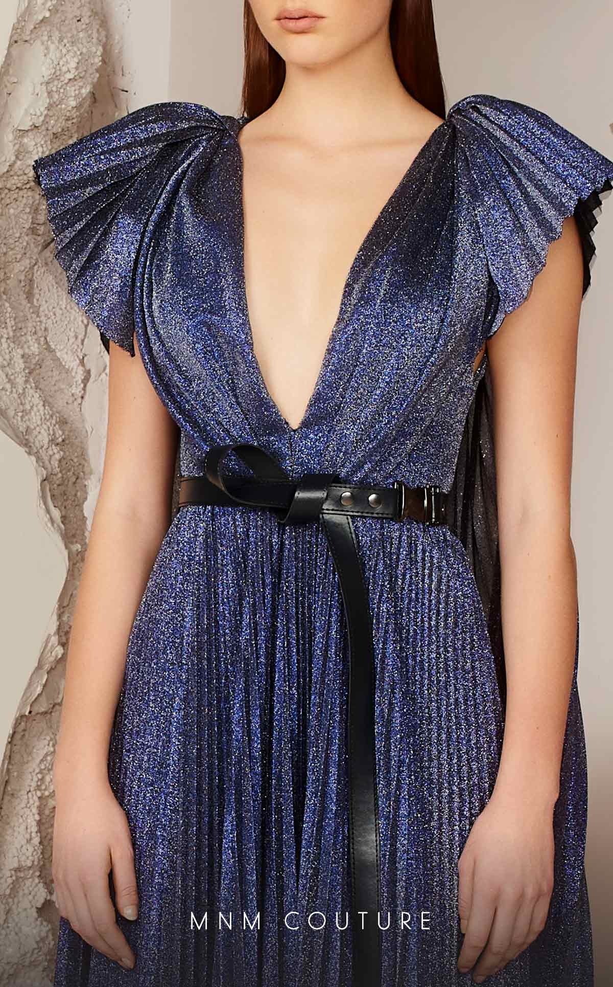 MNM Couture E0018 boasts a trending metallic fabric with a deep V neckline and low back, belted waist with butterfly sleeve details with a beautiful cape falling to the floor.