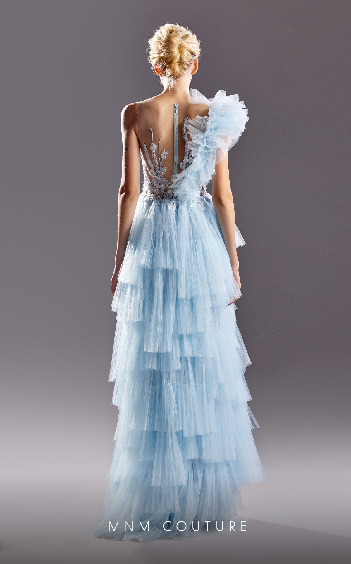 G1528 MNM Couture one shoulder blue tiered long dress boasts a sheer bodice with intricate beaded detailing crawling upwards creating an incredible flattering pattern for your figure